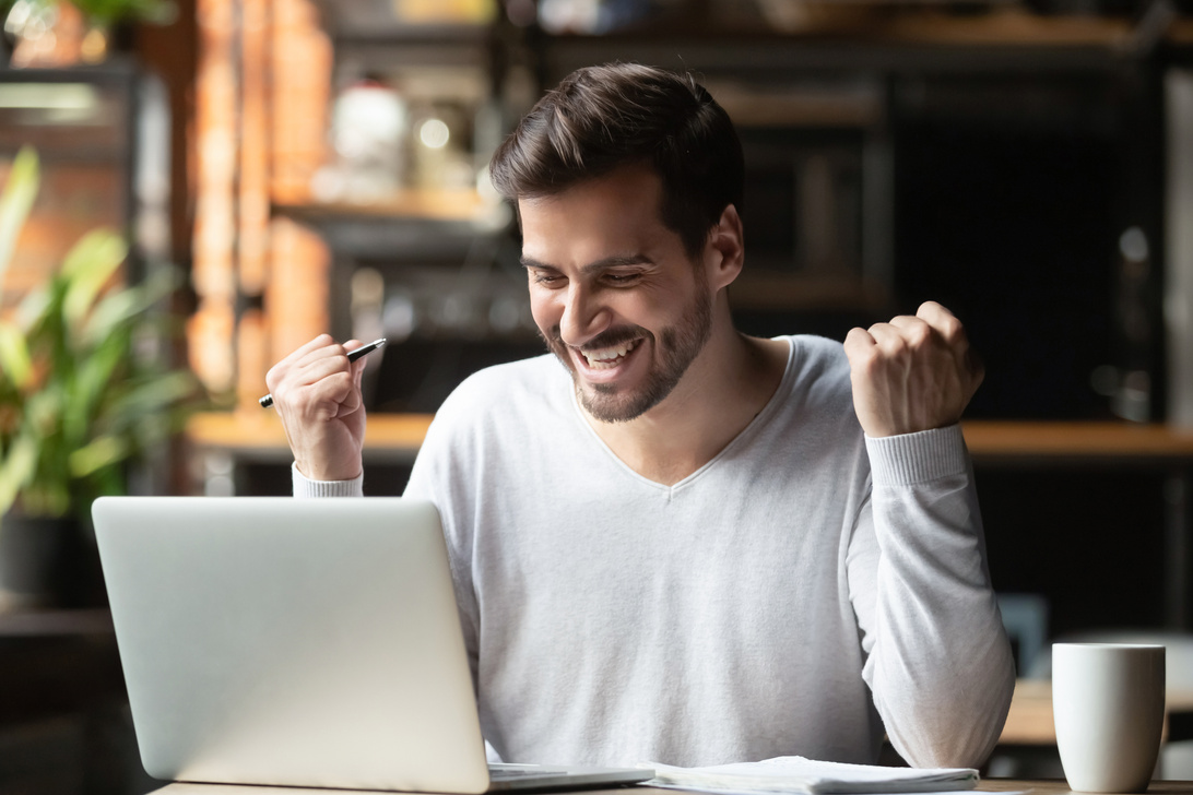 Excited business man winner looking at laptop celebrate online win